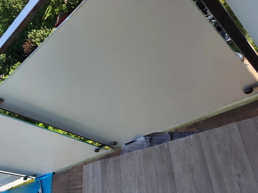 Nowa folia mrożona na szklanej balustradzie balkonowej, widok od dołu